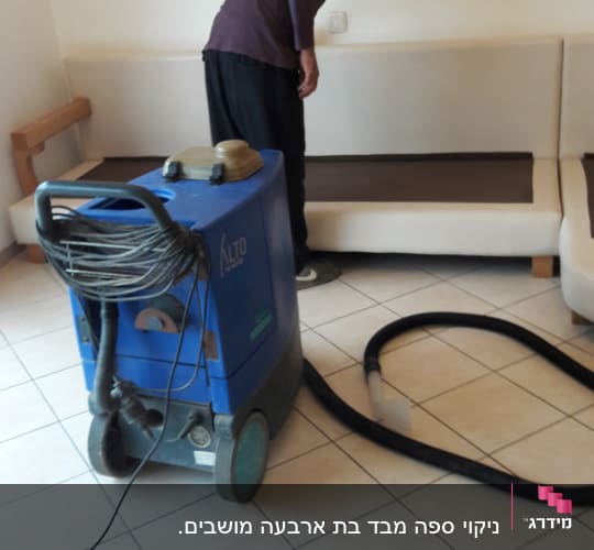 אדם מנקה ספה עם מכונת ניקוי כחולה